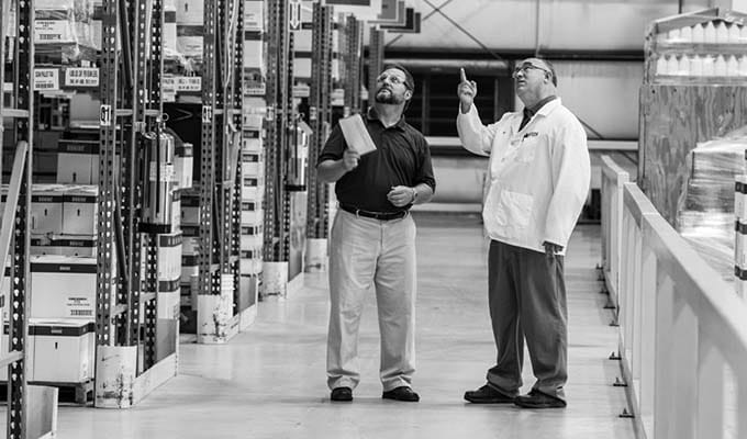 Black and white view of inside of a warehouse of two people talking