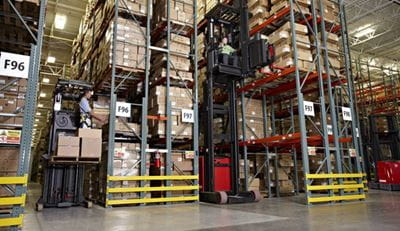 Image shows a high capacity reach truck in operation in a warehouse