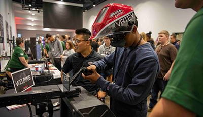 Photo of a man wearing a welding helmet at a presentation booth