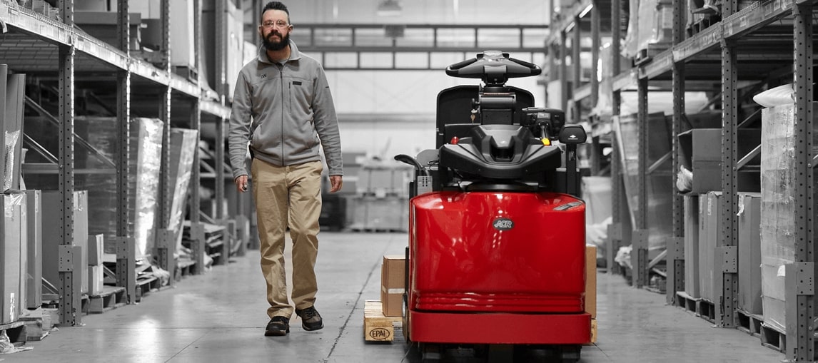 Image of Raymond Forklift equipped with Advance Operator Assist Technology with operator walking parallel to the truck in a warehouse. 