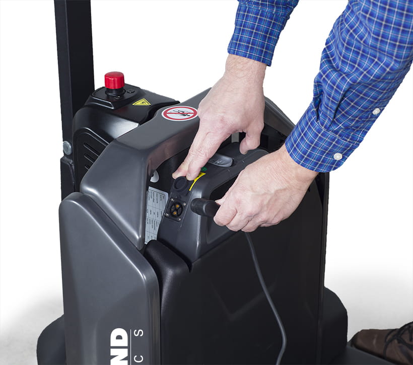 Operator plugging in charger on Raymond Basics electric pallet jack battery compartment